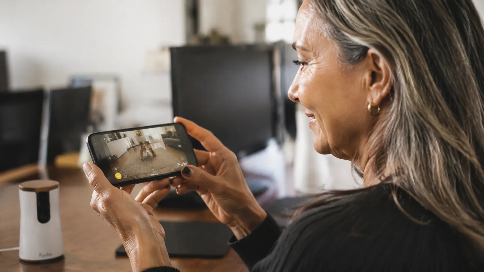 Person checking a pet camera app on their phone while at an office desk